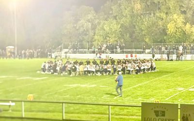 The Copperheads and the Rams set rivalries aside as they kneel in a circle at midfield during their Friday, Sept. 11 game in Missoula as they offer a moment of silence for the 25th anniversary of the 9/11 terrorist attacks. Photo courtesy of Anaconda Junior/Senior High School.