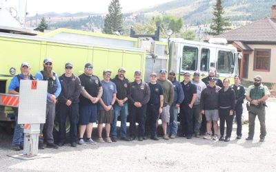 Local law enforcement and firefighters/EMTs gather in front of the Anaconda Fire Department's ladder truck as it flies a large American flag on Friday, Sept. 11, 2026 during a free cookout for first responders provided by the Acacia Lodge No. 33 of the Masonic Temple in commemoration of the 25th anniversary of the 9/11 terrorist attacks. Anaconda Weekly Review photo by James S. Rosien.